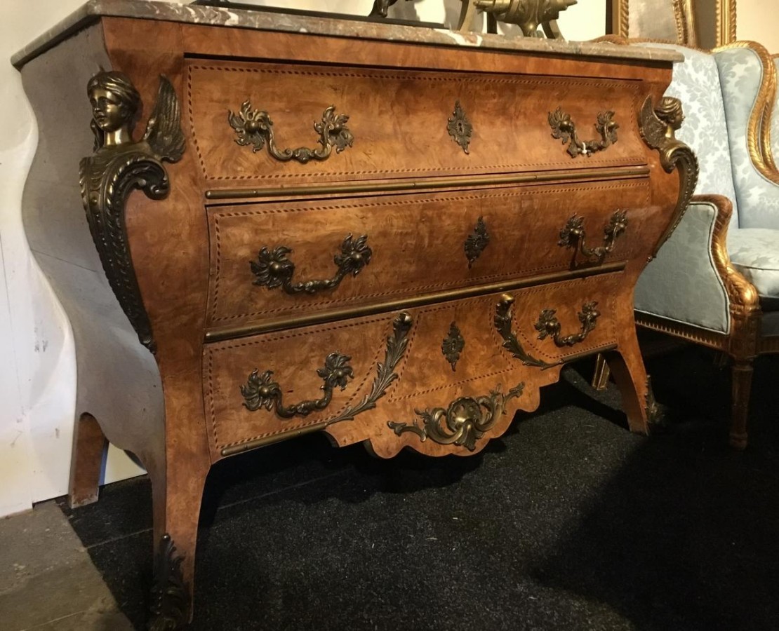 A Chest Of Drawers With Large Bronze Decorations And Marble Top