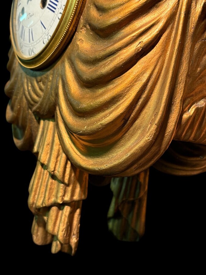 Elegant 19th-century gilt wooden eagle clock with drapery Decorative clock in gilt wood and paste depicting an eagle carrying a large drapery that falls to the left and right of the dial. In normal condition with a few small flaws on the wood.