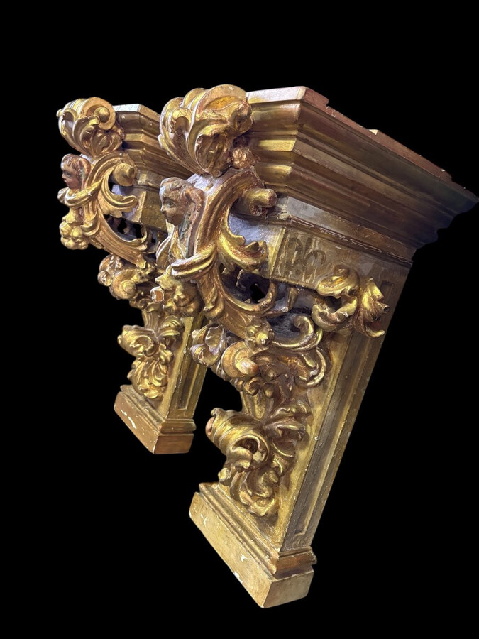 Pair of 17th-century Italian Baroque consoles. Decorative consoles carved in wood, gilded/polychrome, with garlands, fruit, angel heads and decorative ornaments. Ideal for creating a beautiful wall console. Both are in good condition, with normal signs of