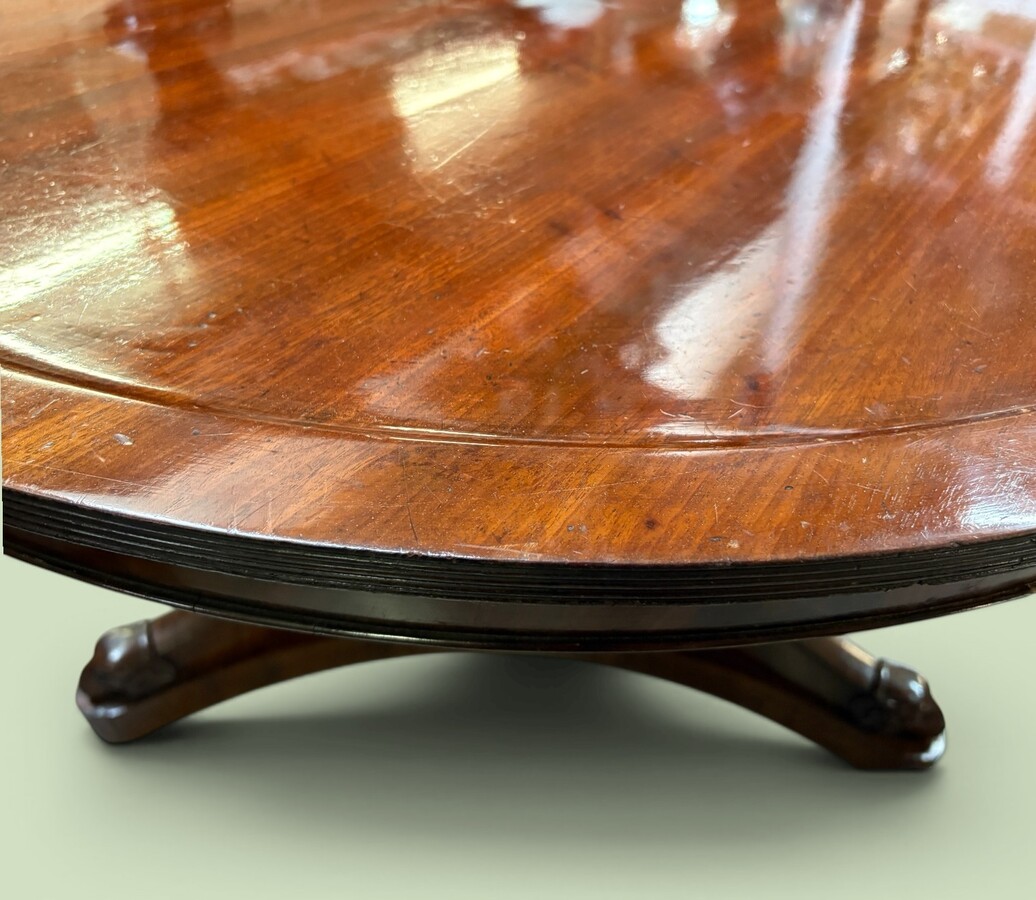  19th-century Charles X-style mahogany pedestal table. Table, featuring three elegant curved legs adorned with ram’s heads. The top is edged with a solid mahogany rim. In good condition, with slight signs of we