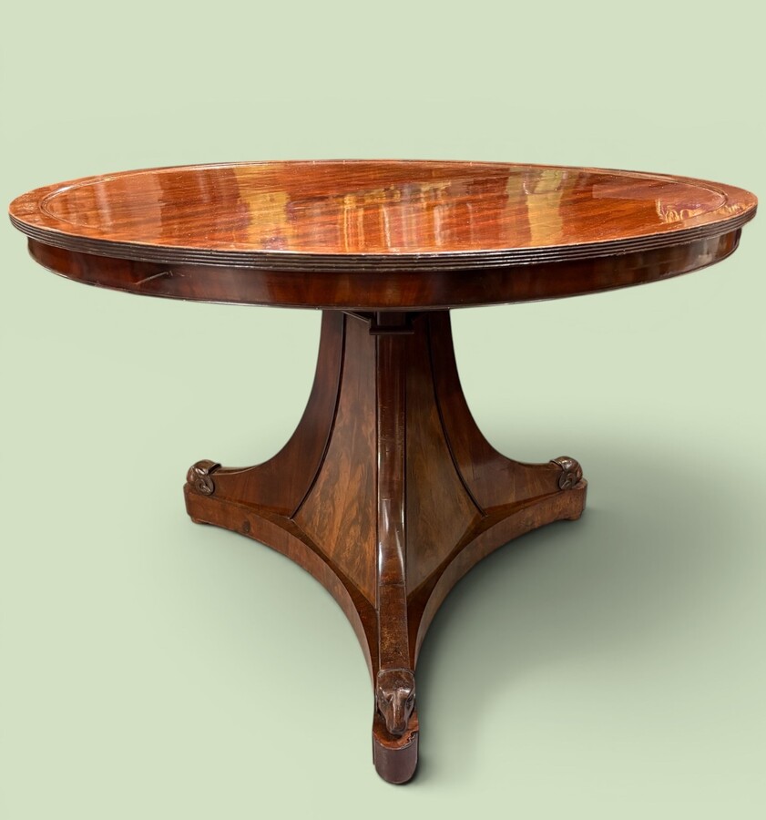  19th-century Charles X-style mahogany pedestal table. Table, featuring three elegant curved legs adorned with ram’s heads. The top is edged with a solid mahogany rim. In good condition, with slight signs of we
