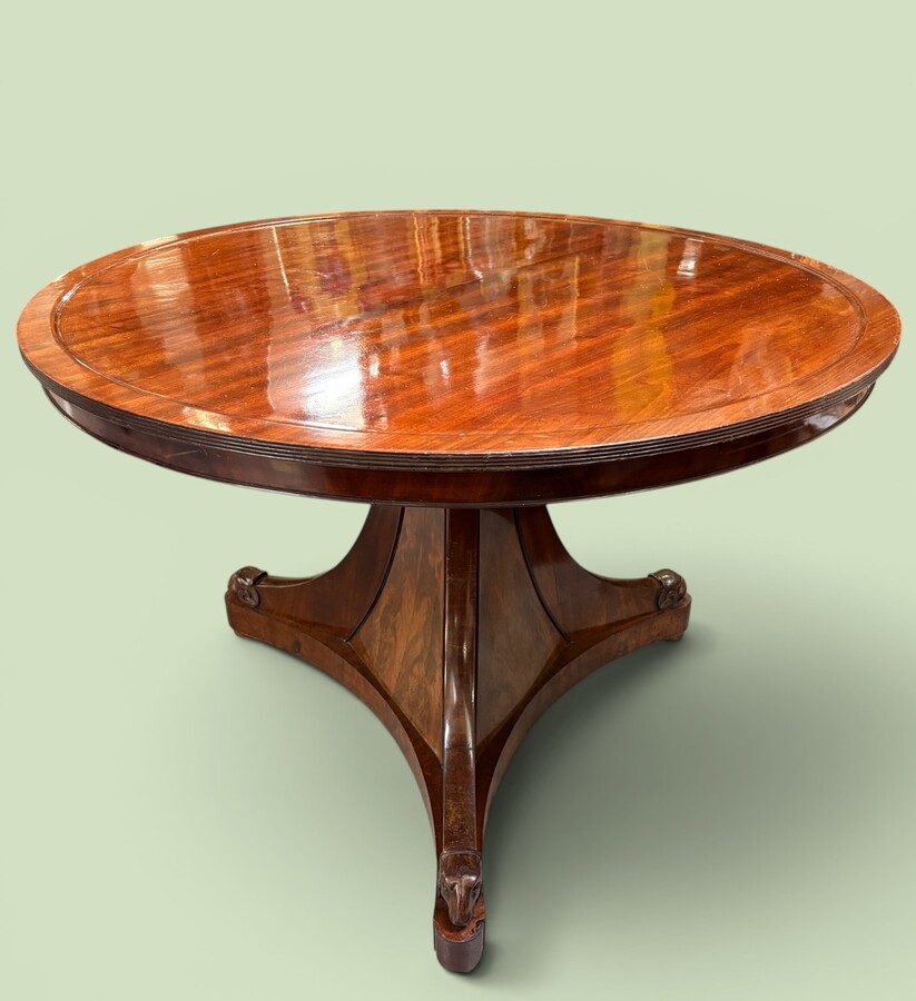  19th-century Charles X-style mahogany pedestal table. Table, featuring three elegant curved legs adorned with ram’s heads. The top is edged with a solid mahogany rim. In good condition, with slight signs of we