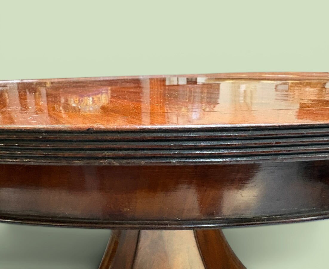  19th-century Charles X-style mahogany pedestal table. Table, featuring three elegant curved legs adorned with ram’s heads. The top is edged with a solid mahogany rim. In good condition, with slight signs of we