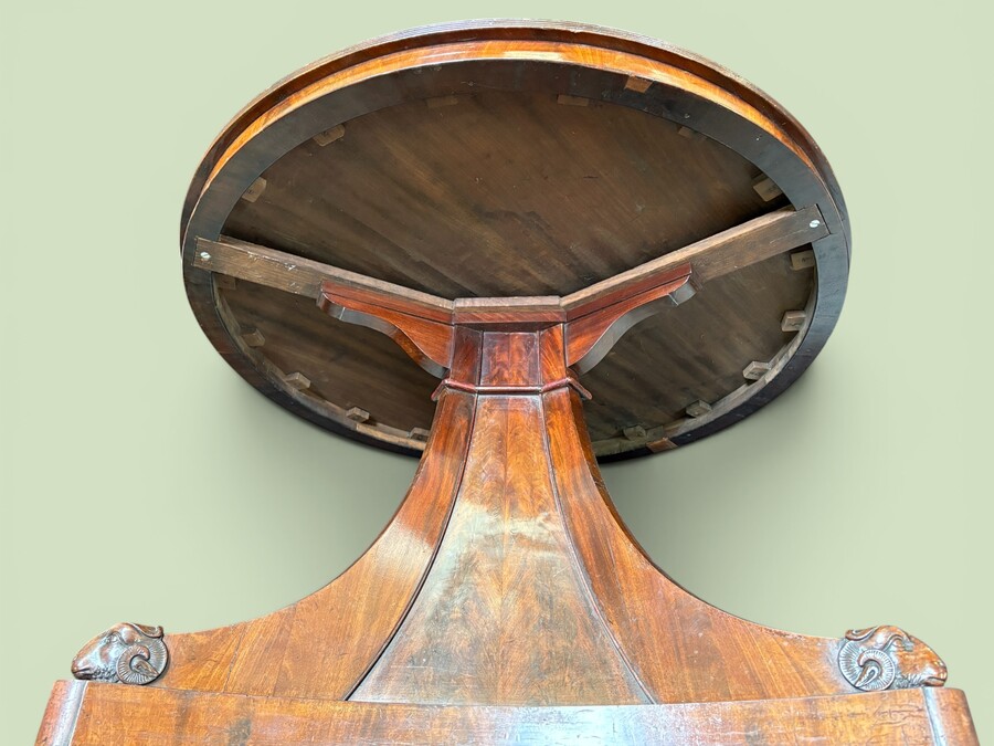  19th-century Charles X-style mahogany pedestal table. Table, featuring three elegant curved legs adorned with ram’s heads. The top is edged with a solid mahogany rim. In good condition, with slight signs of we