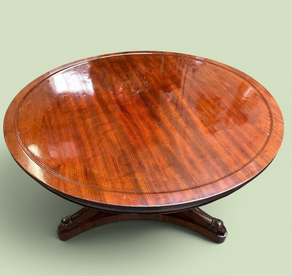  19th-century Charles X-style mahogany pedestal table. Table, featuring three elegant curved legs adorned with ram’s heads. The top is edged with a solid mahogany rim. In good condition, with slight signs of we