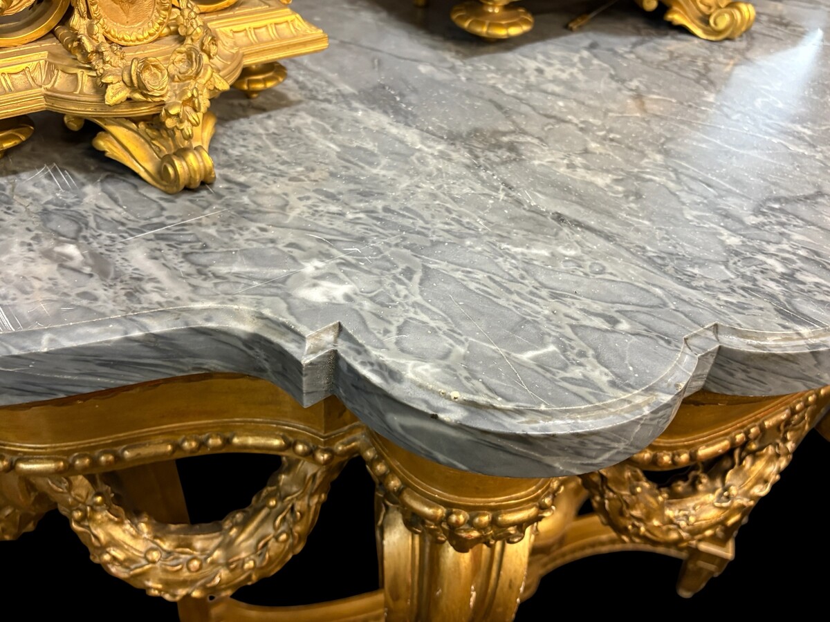  19th-century Louis XVI-style console table in gilded wood. The console features four legs decorated with garlands and a large vase at the base, topped with a superb 3 cm thick grey marble top. The console and marble top are in good condition, w