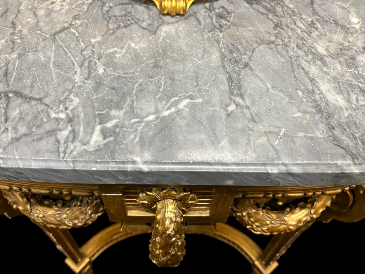 19th-century Louis XVI-style console table in gilded wood. The console features four legs decorated with garlands and a large vase at the base, topped with a superb 3 cm thick grey marble top. The console and marble top are in good condition
