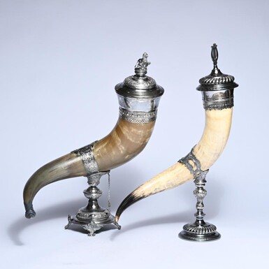2 drinking horns on silver-plated bases, made from polished horn, with richly detailed mounts and removable lids Dimensions: 59.5 and 60 cm in height 2 highly decorative drinking horns on silver-plated bases, late 19th century.