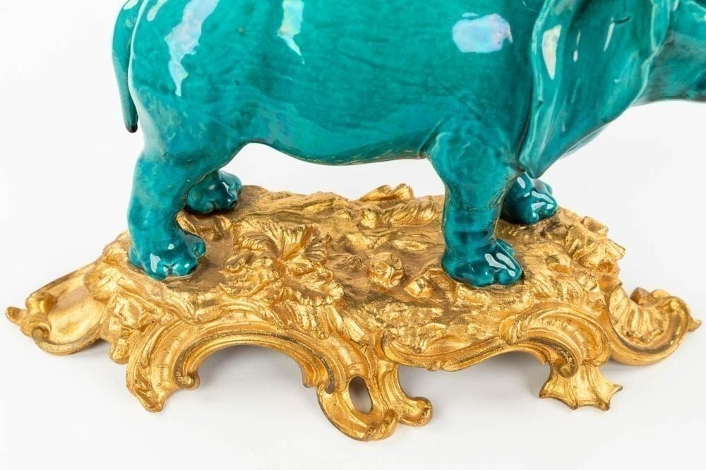 A Ceramic Statue Of An Elephant , Mounted On A Gilded Bronze Base. Decorative Sculpture Signed Below The Base L. Rocher , 20thC. Dimensions : Height : 30 Cm Wide : 35 Cm Depth : 15 Cm In Very Good Condition