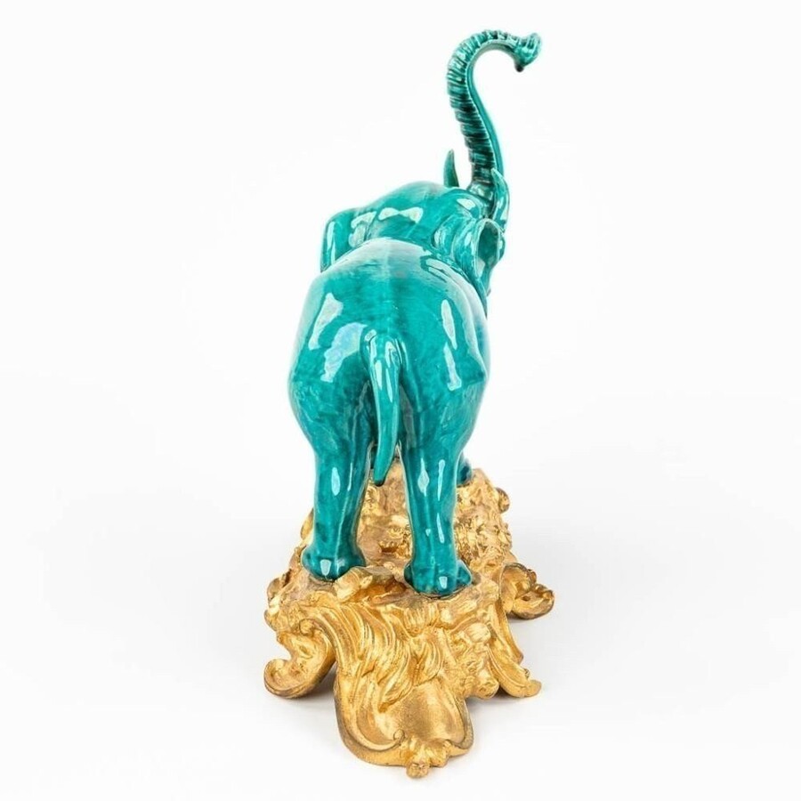 A Ceramic Statue Of An Elephant , Mounted On A Gilded Bronze Base. Decorative Sculpture Signed Below The Base L. Rocher , 20thC. Dimensions : Height : 30 Cm Wide : 35 Cm Depth : 15 Cm In Very Good Condition