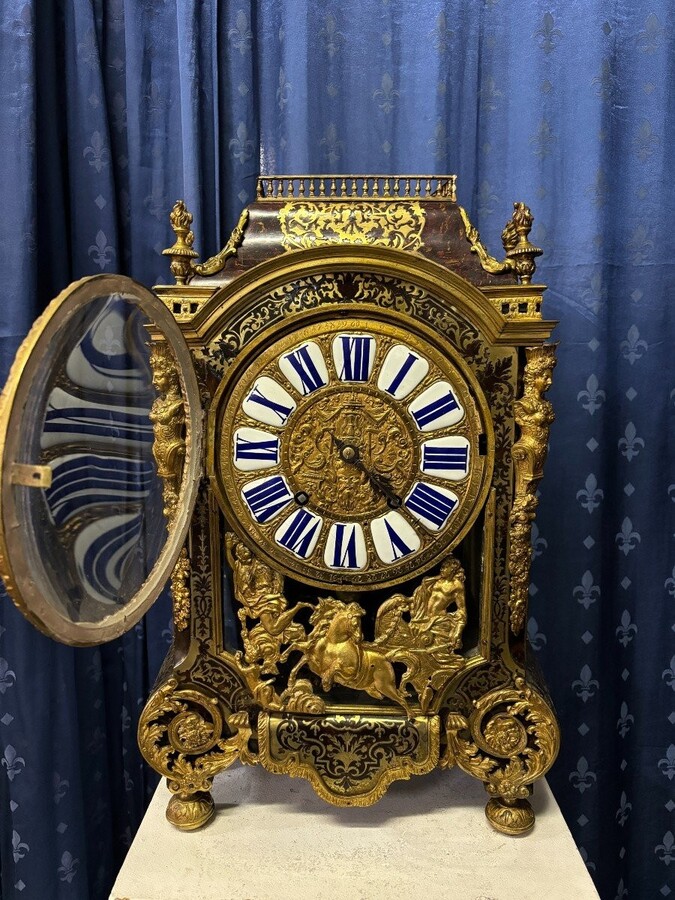A large brass inlaid cartel on a tortoiseshell background, 18th century, Régence period. Rectangular cartel ending in scrolls decorated with gilt bronze on the front and a tripod in the centre. Gilt bronze dial with enamelled cartouches