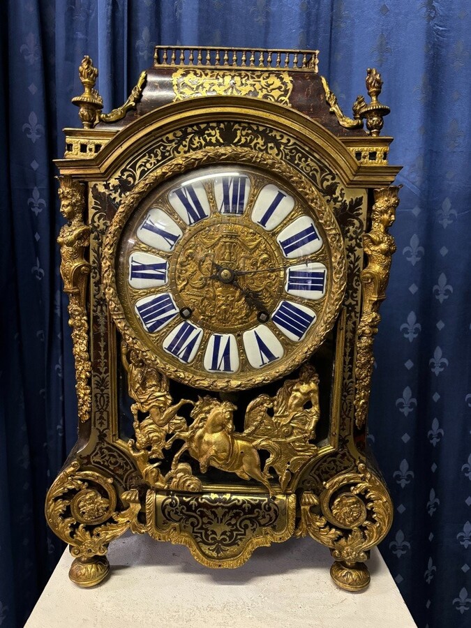 A large brass inlaid cartel on a tortoiseshell background, 18th century, Régence period. Rectangular cartel ending in scrolls decorated with gilt bronze on the front and a tripod in the centre. Gilt bronze dial with enamelled cartouches