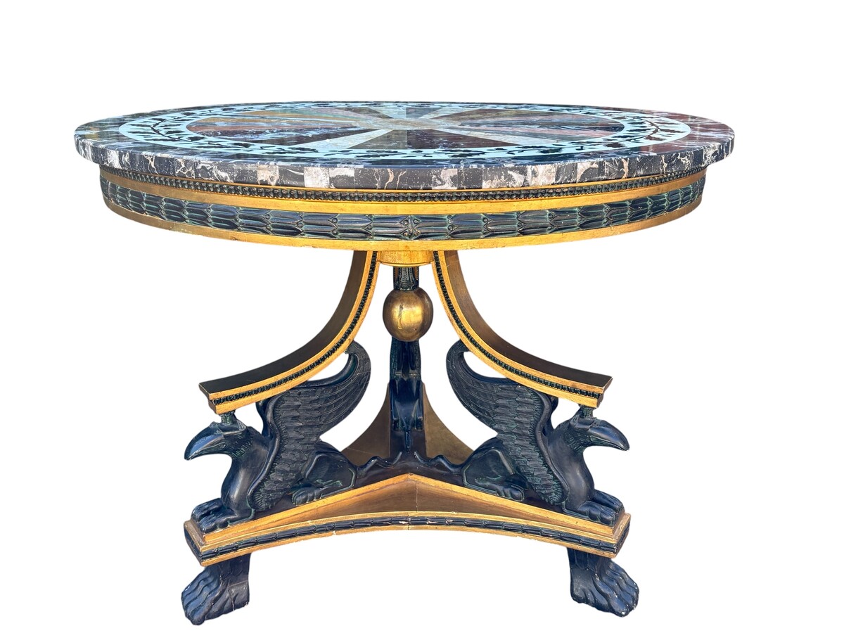 A lovely Empire-style center table, 1830–1840 A highly decorative center table in patinated and gilded wood, comprising a three-legged base adorned with three reclining winged mythological creatures and a suspended gilded wooden sphere