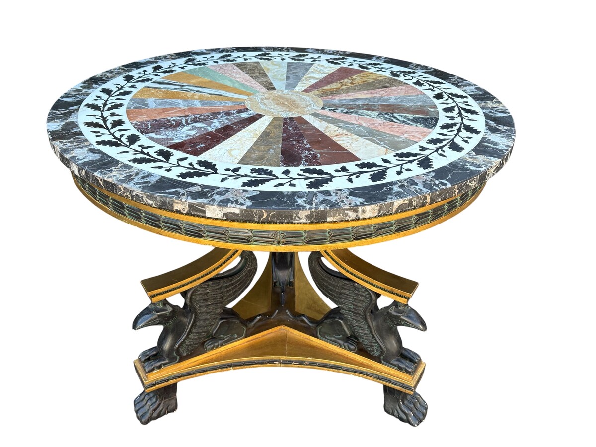 A lovely Empire-style center table, 1830–1840 A highly decorative center table in patinated and gilded wood, comprising a three-legged base adorned with three reclining winged mythological creatures and a suspended gilded wooden sphere