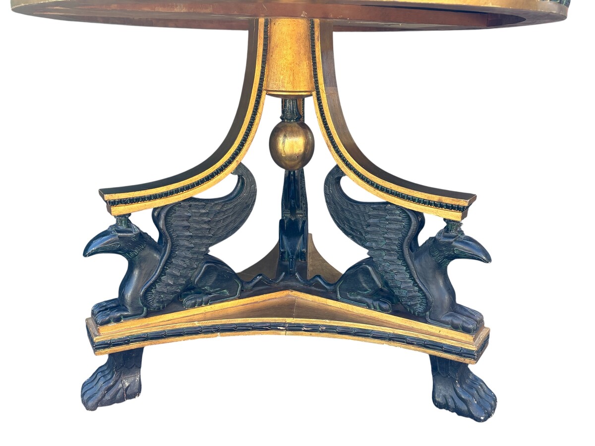 A lovely Empire-style center table, 1830–1840 A highly decorative center table in patinated and gilded wood, comprising a three-legged base adorned with three reclining winged mythological creatures and a suspended gilded wooden sphere