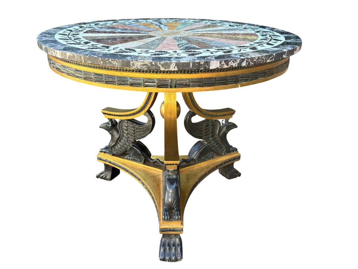A lovely Empire-style center table, 1830–1840 A highly decorative center table in patinated and gilded wood, comprising a three-legged base adorned with three reclining winged mythological creatures and a suspended gilded wooden sphere