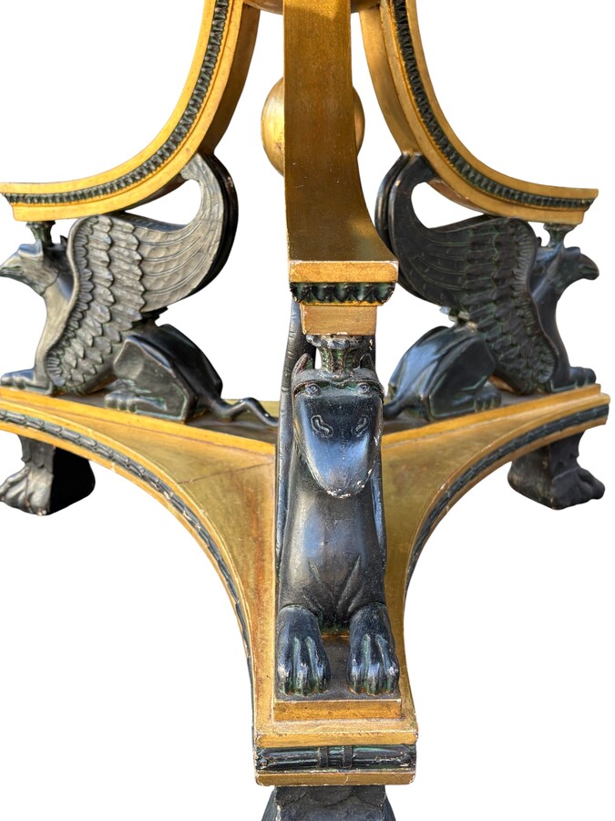 A lovely Empire-style center table, 1830–1840 A highly decorative center table in patinated and gilded wood, comprising a three-legged base adorned with three reclining winged mythological creatures and a suspended gilded wooden sphere