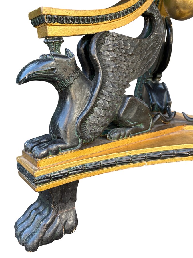 A lovely Empire-style center table, 1830–1840 A highly decorative center table in patinated and gilded wood, comprising a three-legged base adorned with three reclining winged mythological creatures and a suspended gilded wooden sphere