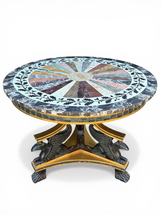 A lovely Empire-style center table, 1830–1840 A highly decorative center table in patinated and gilded wood, comprising a three-legged base adorned with three reclining winged mythological creatures and a suspended gilded wooden sphere