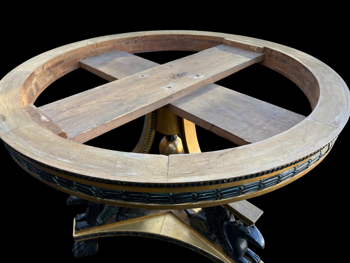 A lovely Empire-style center table, 1830–1840 A highly decorative center table in patinated and gilded wood, comprising a three-legged base adorned with three reclining winged mythological creatures and a suspended gilded wooden sphere