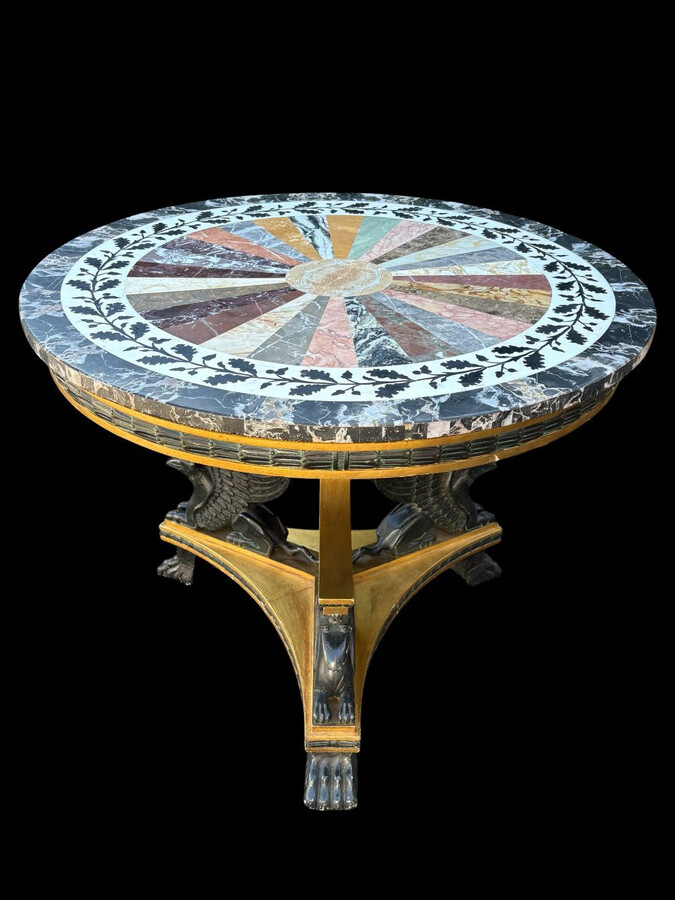A lovely Empire-style center table, 1830–1840 A highly decorative center table in patinated and gilded wood, comprising a three-legged base adorned with three reclining winged mythological creatures and a suspended gilded wooden sphere