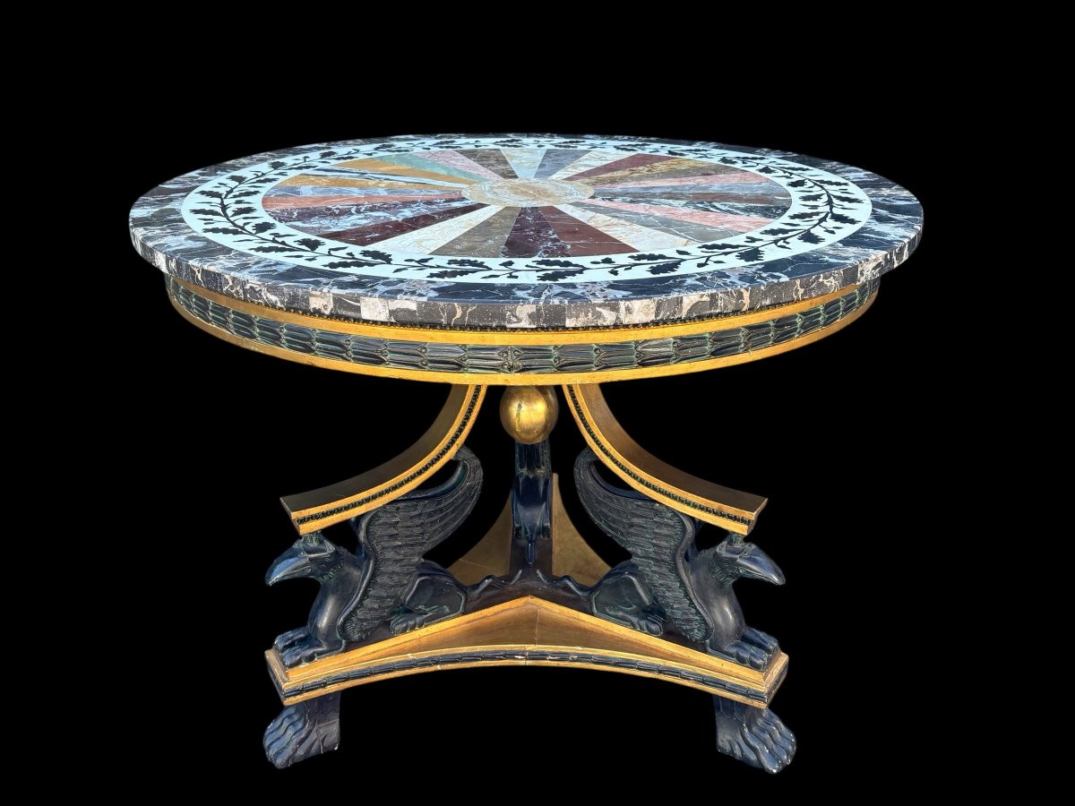 A lovely Empire-style center table, 1830–1840 A highly decorative center table in patinated and gilded wood, comprising a three-legged base adorned with three reclining winged mythological creatures and a suspended gilded wooden sphere