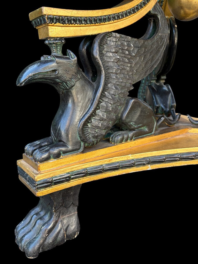 A lovely Empire-style center table, 1830–1840 A highly decorative center table in patinated and gilded wood, comprising a three-legged base adorned with three reclining winged mythological creatures and a suspended gilded wooden sphere