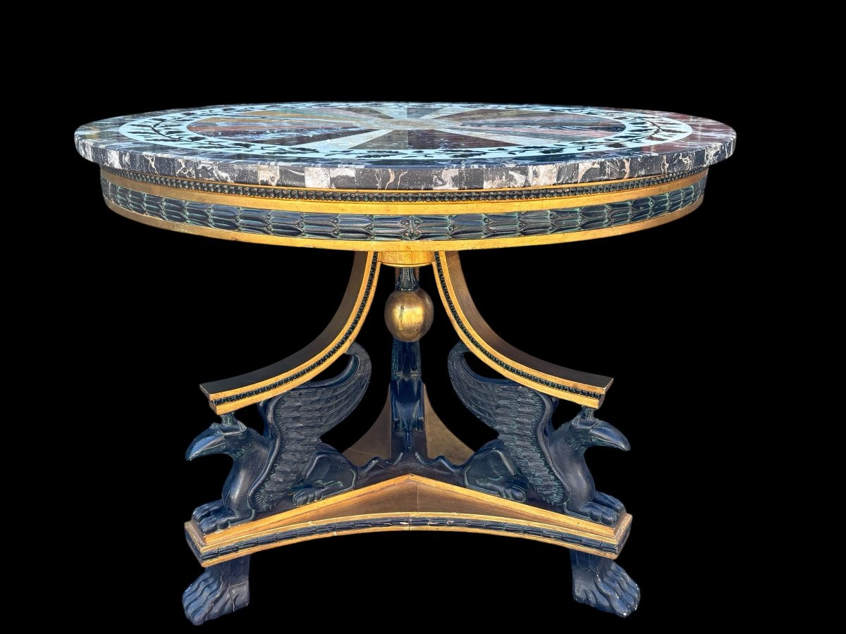 A lovely Empire-style center table, 1830–1840 A highly decorative center table in patinated and gilded wood, comprising a three-legged base adorned with three reclining winged mythological creatures and a suspended gilded wooden sphere