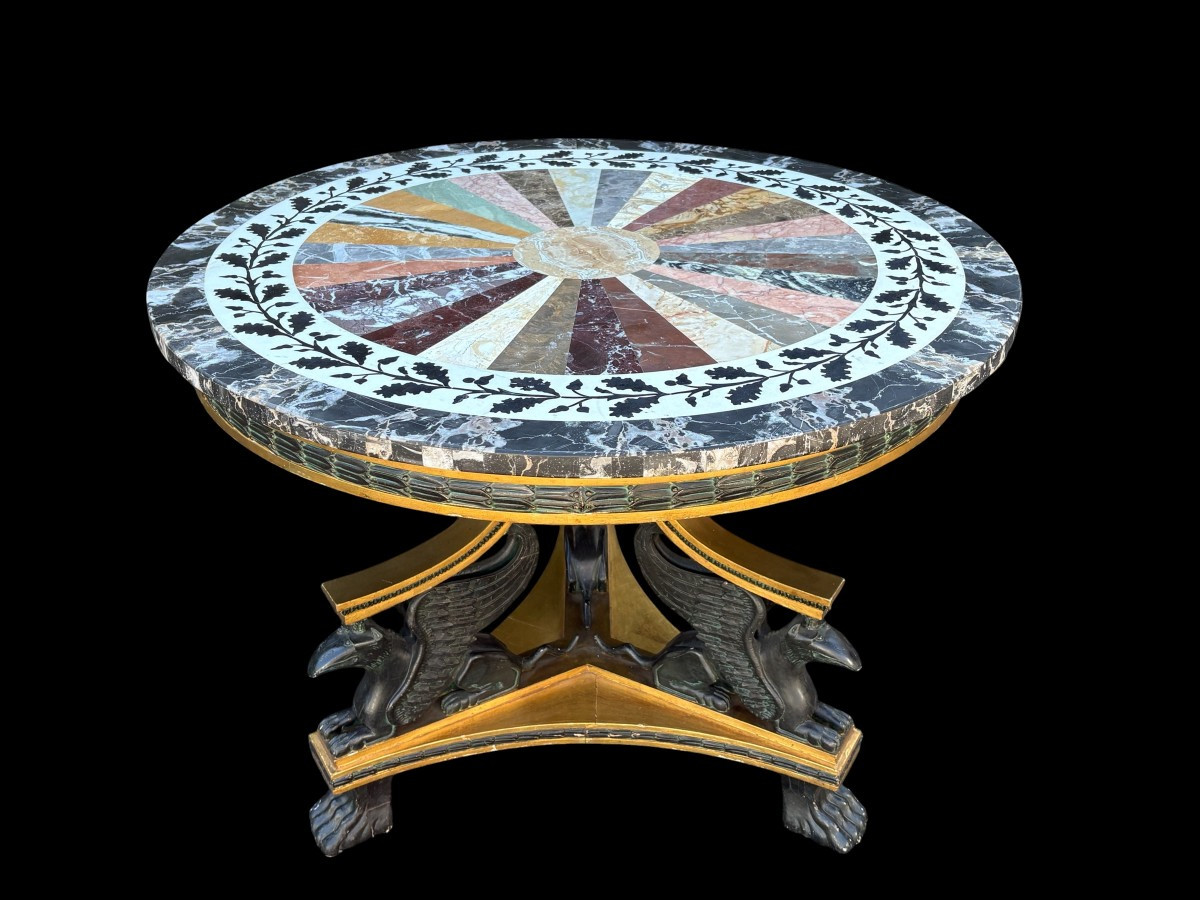 A lovely Empire-style center table, 1830–1840 A highly decorative center table in patinated and gilded wood, comprising a three-legged base adorned with three reclining winged mythological creatures and a suspended gilded wooden sphere