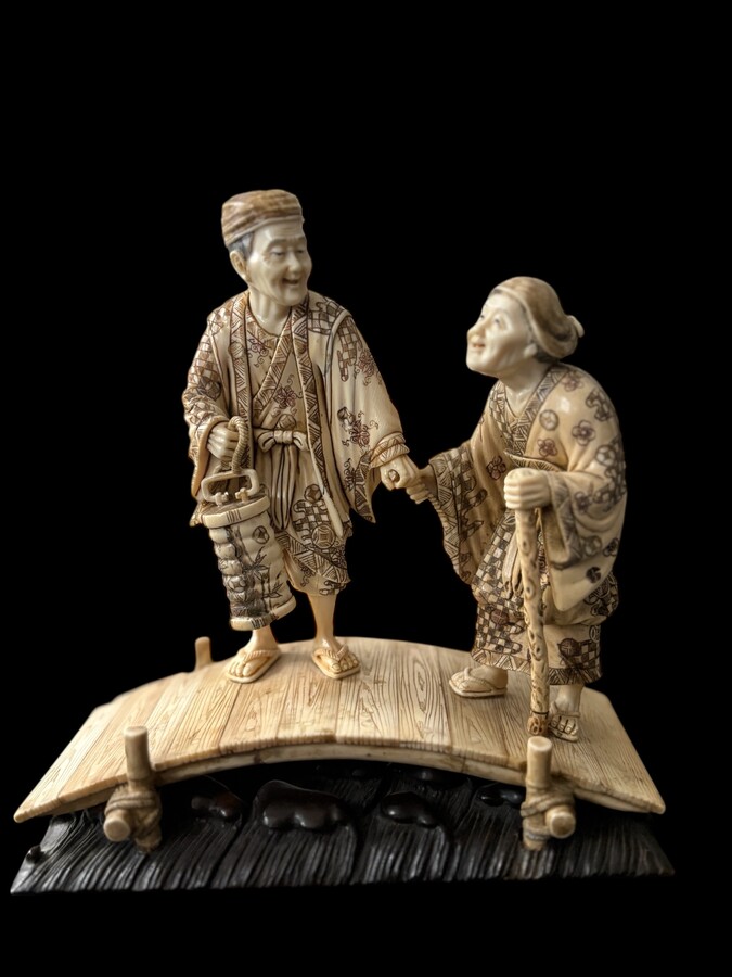 A nice ivory sculpture, China, 19th century An ivory sculpture with very fine detail depicting an elderly couple in kimonos walking across a bridge over water The water beneath the bridge is carved from wood. Dimensions: Width: 17 cm Height: 18 cm