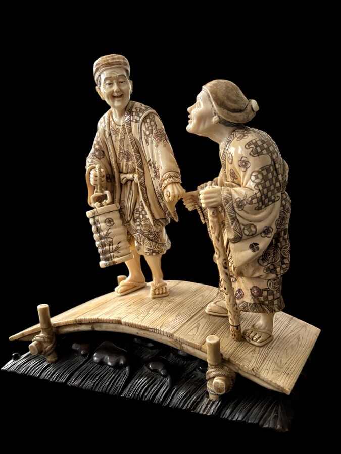 A nice ivory sculpture, China, 19th century An ivory sculpture with very fine detail depicting an elderly couple in kimonos walking across a bridge over water The water beneath the bridge is carved from wood. Dimensions: Width: 17 cm Height: 18 cm