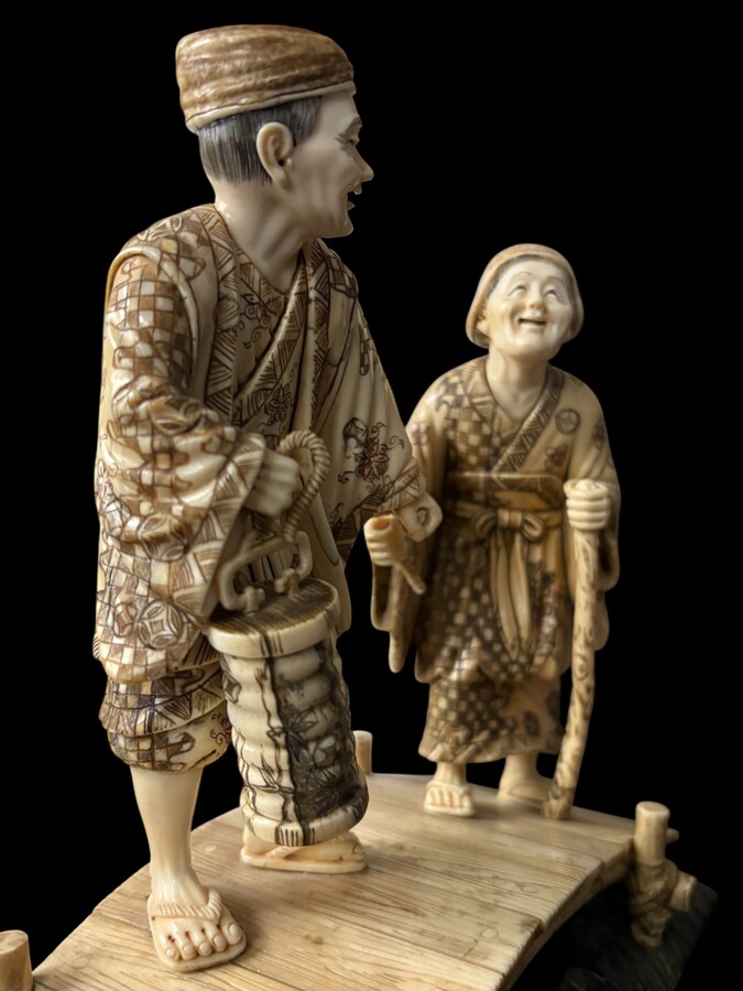 A nice ivory sculpture, China, 19th century An ivory sculpture with very fine detail depicting an elderly couple in kimonos walking across a bridge over water The water beneath the bridge is carved from wood. Dimensions: Width: 17 cm Height: 18 cm