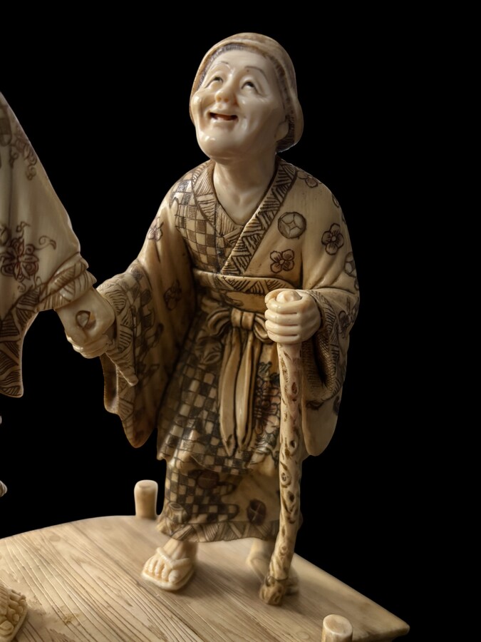 A nice ivory sculpture, China, 19th century An ivory sculpture with very fine detail depicting an elderly couple in kimonos walking across a bridge over water The water beneath the bridge is carved from wood. Dimensions: Width: 17 cm Height: 18 cm
