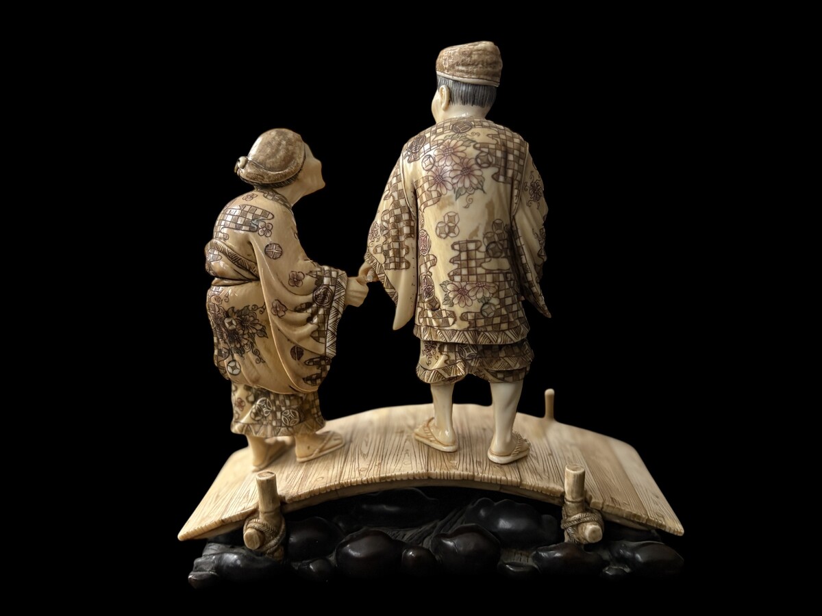 A nice ivory sculpture, China, 19th century An ivory sculpture with very fine detail depicting an elderly couple in kimonos walking across a bridge over water The water beneath the bridge is carved from wood. Dimensions: Width: 17 cm Height: 18 cm