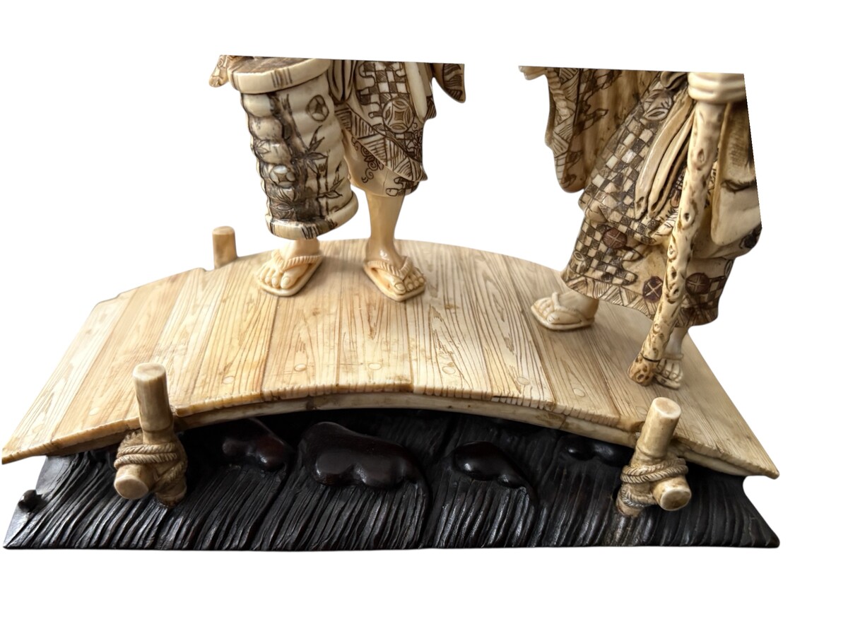 A nice ivory sculpture, China, 19th century An ivory sculpture with very fine detail depicting an elderly couple in kimonos walking across a bridge over water The water beneath the bridge is carved from wood. Dimensions: Width: 17 cm Height: 18 cm
