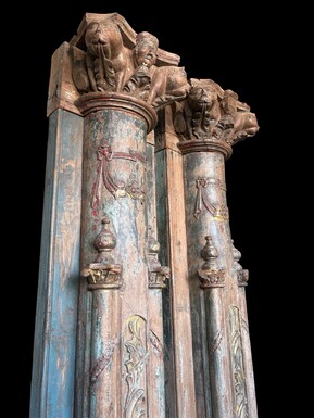 A pair of large decorative wooden columns with 19th-century capitals.Nice columns showing traces of their former polychrome finish, comprising three parts: a carved wooden capital, a decorated column and a stone plinth. In normal condition.