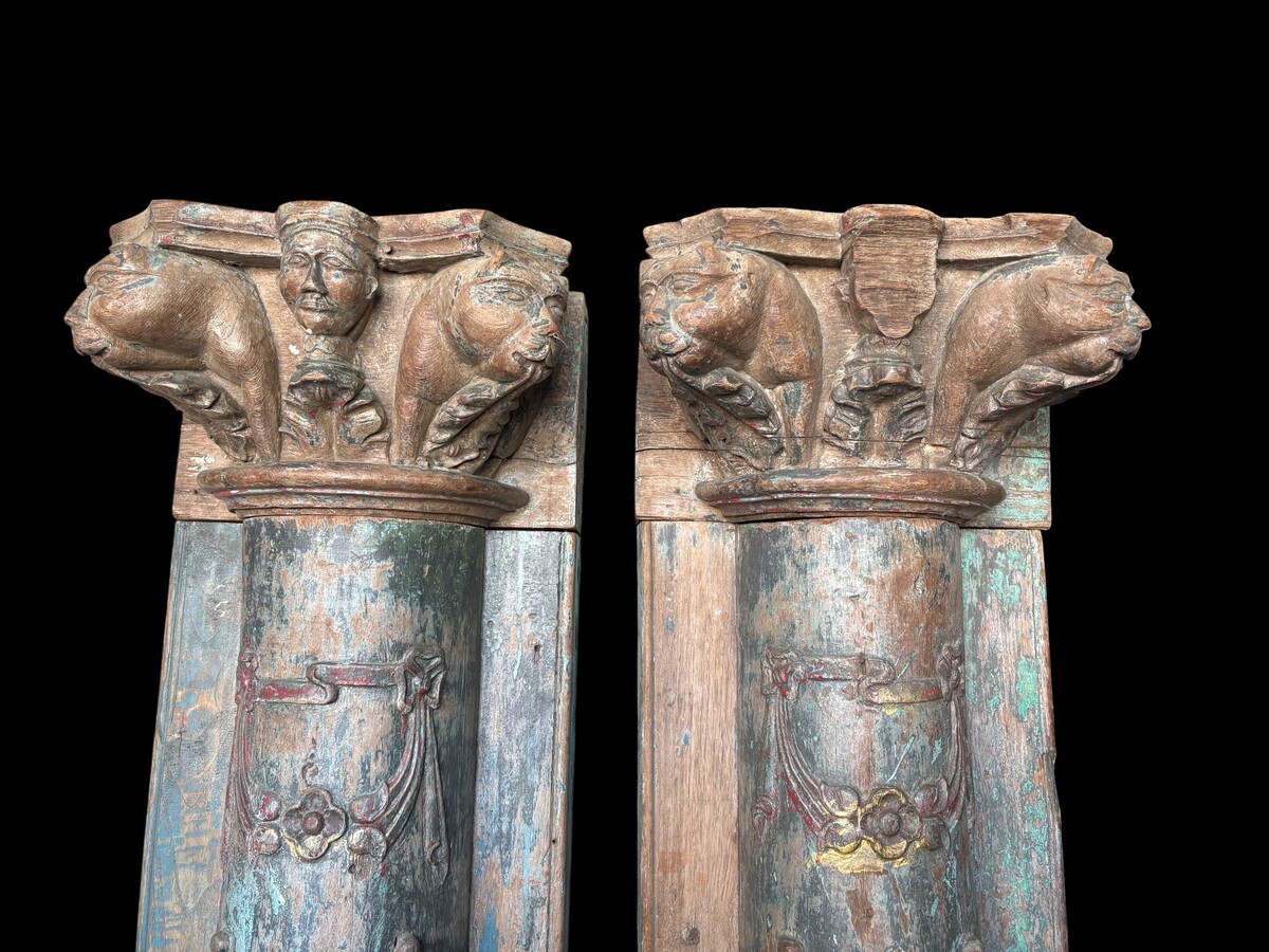 A pair of large decorative wooden columns with 19th-century capitals.Nice columns showing traces of their former polychrome finish, comprising three parts: a carved wooden capital, a decorated column and a stone plinth. In normal condition.