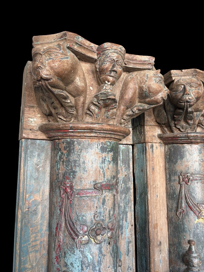 A pair of large decorative wooden columns with 19th-century capitals.Nice columns showing traces of their former polychrome finish, comprising three parts: a carved wooden capital, a decorated column and a stone plinth. In normal condition.