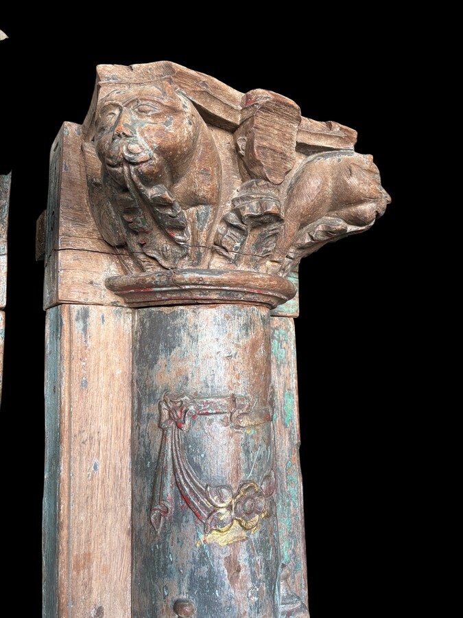A pair of large decorative wooden columns with 19th-century capitals.Nice columns showing traces of their former polychrome finish, comprising three parts: a carved wooden capital, a decorated column and a stone plinth. In normal condition.