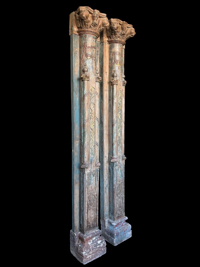 A pair of large decorative wooden columns with 19th-century capitals.Nice columns showing traces of their former polychrome finish, comprising three parts: a carved wooden capital, a decorated column and a stone plinth. In normal condition.