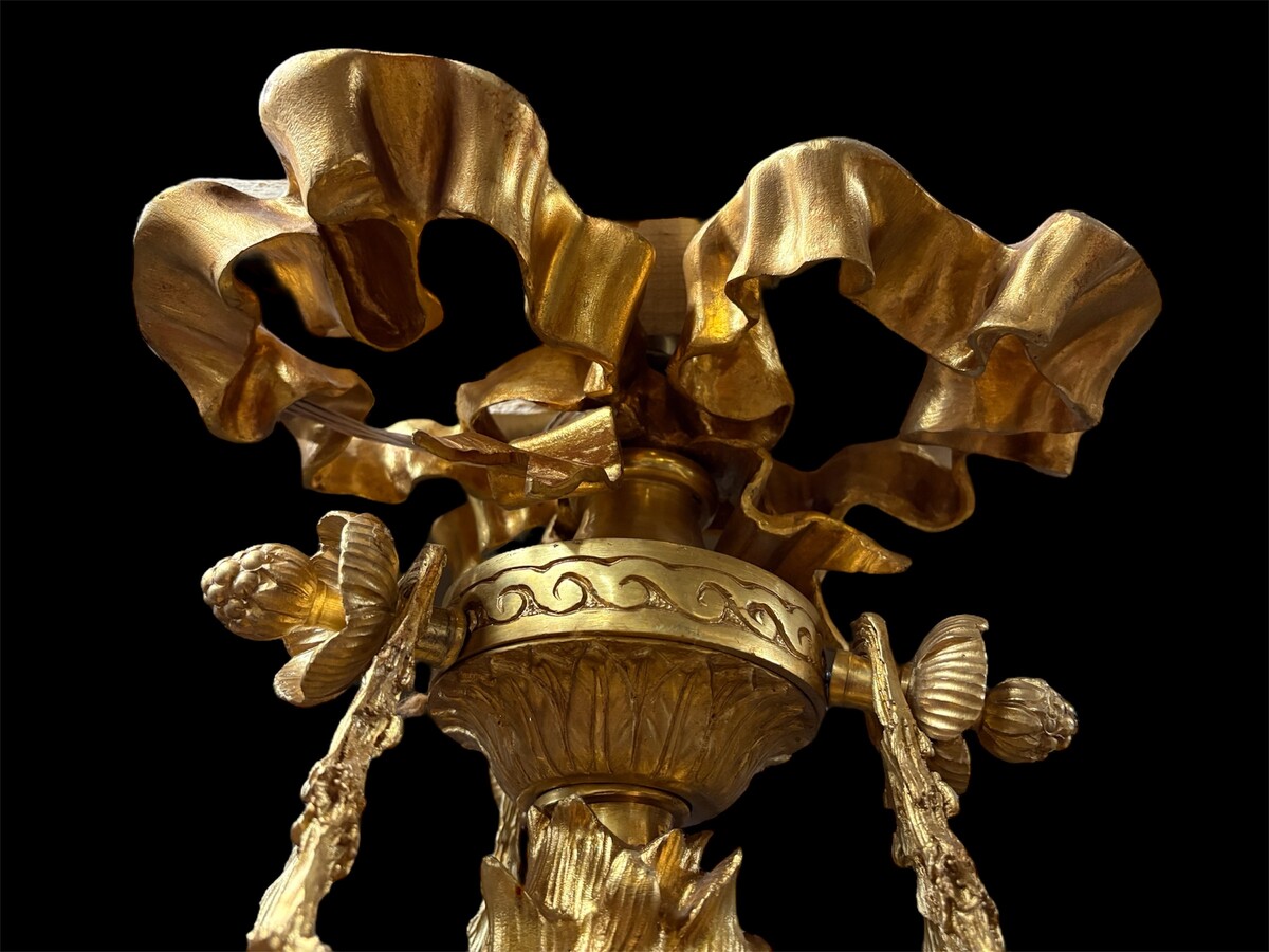 A pair of large gilded bronze chandeliers depicting three mythological women , 20thC. Nice chandeliers with 15 light points, featuring three mythological women holding a bouquet of flowers; at the top, a large Louis XVI-style bow 
