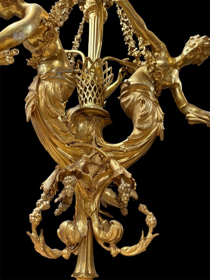 A pair of large gilded bronze chandeliers depicting three mythological women , 20thC. Nice chandeliers with 15 light points, featuring three mythological women holding a bouquet of flowers; at the top, a large Louis XVI-style bow 