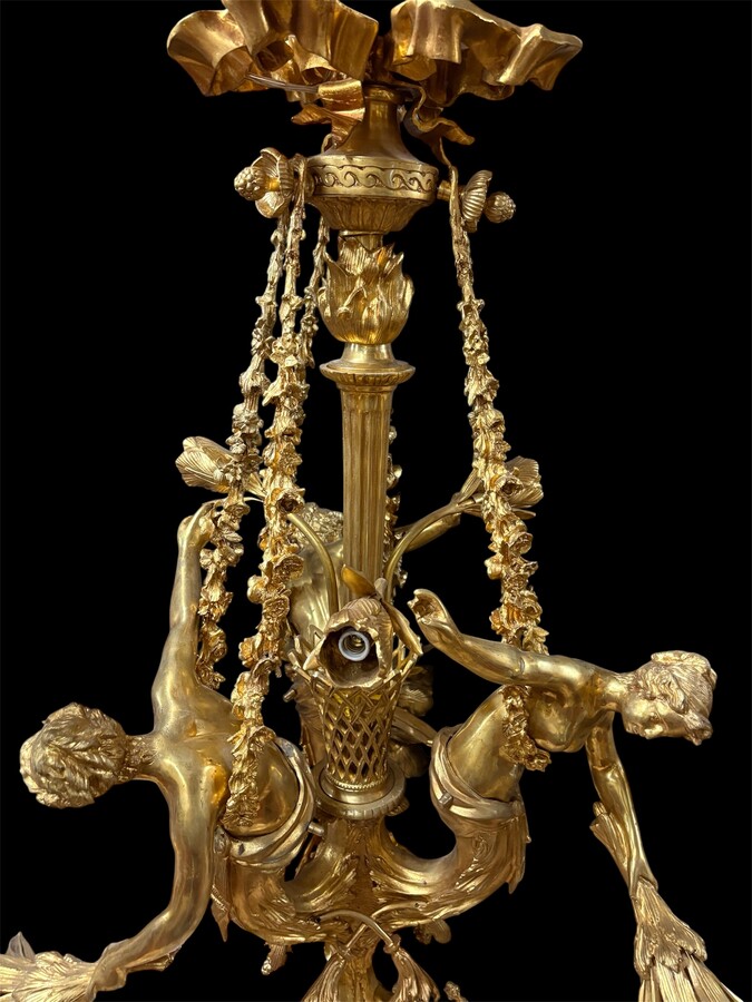A pair of large gilded bronze chandeliers depicting three mythological women , 20thC. Nice chandeliers with 15 light points, featuring three mythological women holding a bouquet of flowers; at the top, a large Louis XVI-style bow 