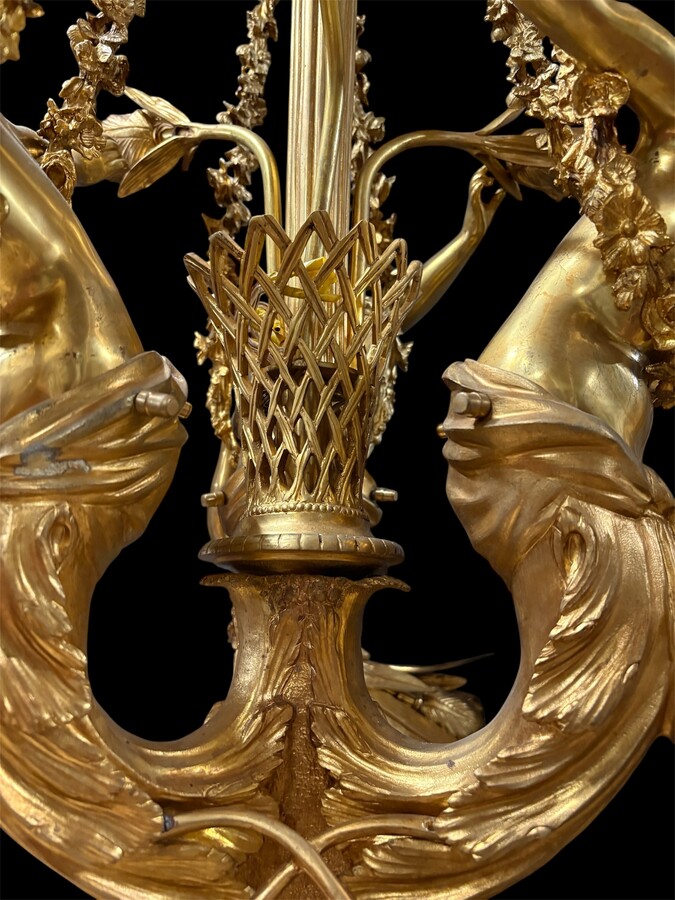 A pair of large gilded bronze chandeliers depicting three mythological women , 20thC. Nice chandeliers with 15 light points, featuring three mythological women holding a bouquet of flowers; at the top, a large Louis XVI-style bow 