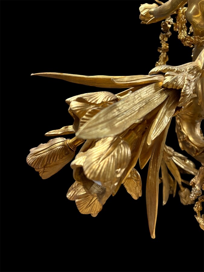 A pair of large gilded bronze chandeliers depicting three mythological women , 20thC. Nice chandeliers with 15 light points, featuring three mythological women holding a bouquet of flowers; at the top, a large Louis XVI-style bow 