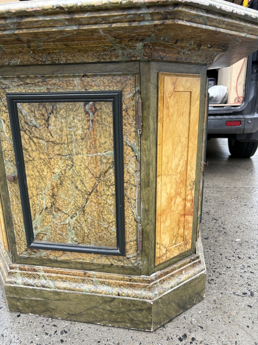 A special table painted to resemble marble 20th century. A decorative piece that can be used as a table, a pedestal or a piece of furniture. It features a triangular wooden top resting on a wooden base fitted with four panelled doors