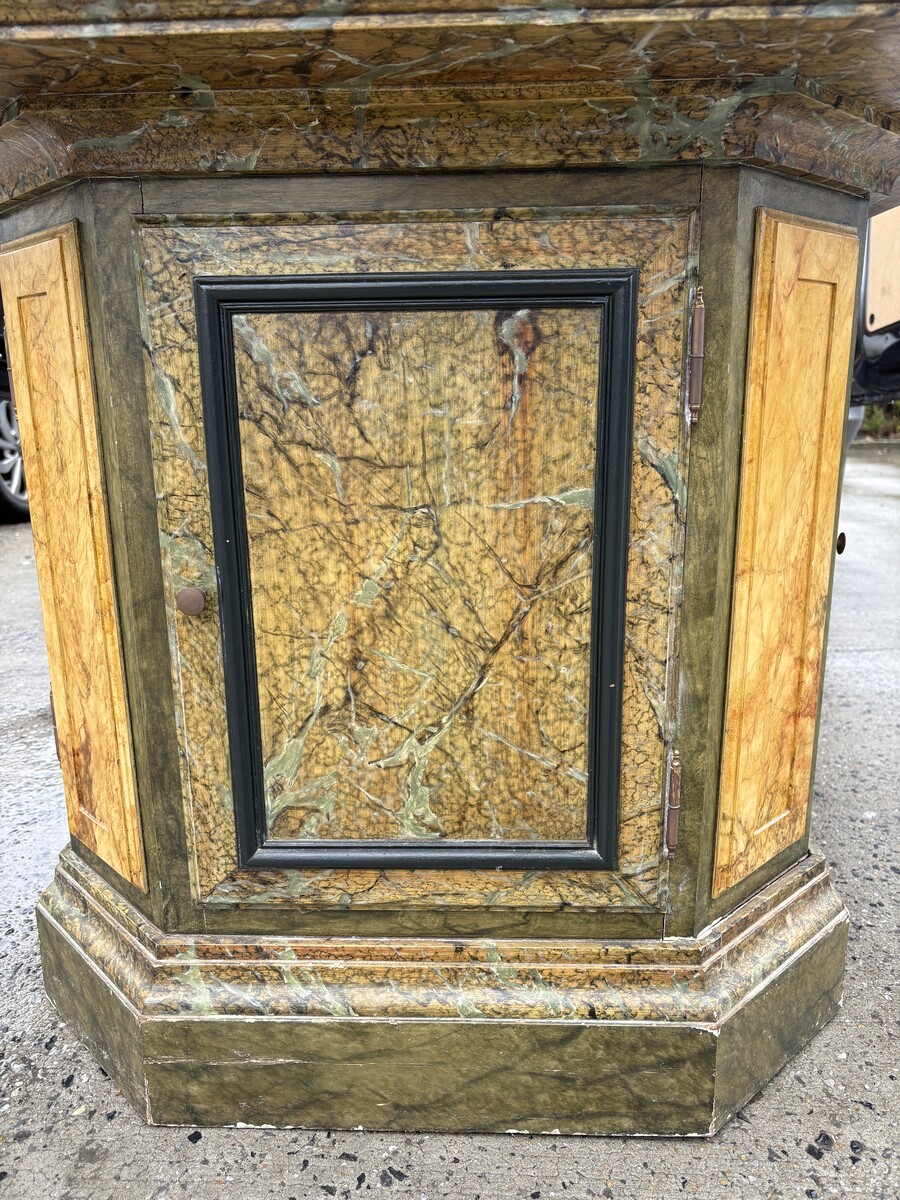 A special table painted to resemble marble 20th century. A decorative piece that can be used as a table, a pedestal or a piece of furniture. It features a triangular wooden top resting on a wooden base fitted with four panelled doors