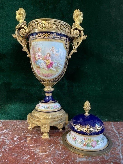 A Very Large Napoleon III Period Vase In Sevres Porcelain Decorated With A Gallant Scene On One Side And A Landscape On The Other Side, Gilded With Gold, Floral Motif And Oven Blue Background. Chased Bronze And Gilt Bronze Mount