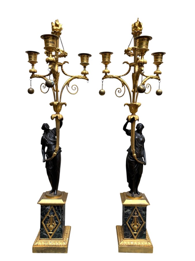 An elegant pair of candelabras in finely chased, gilded and patinated bronze. The shaft is adorned with an antique draped female figure, resting on a green marble base. In the Louis XVI style, these pieces date from the early 19th century. 