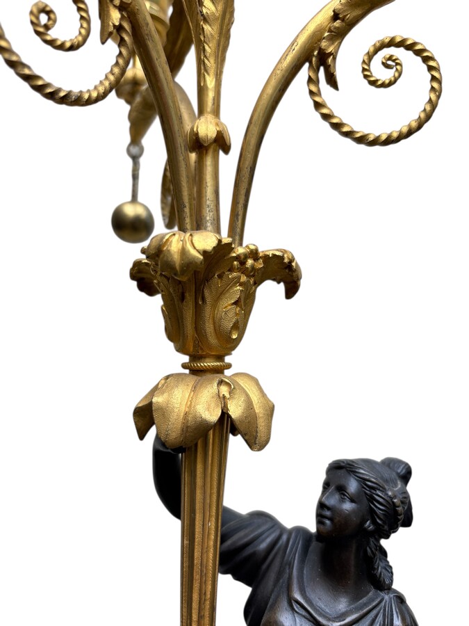 An elegant pair of candelabras in finely chased, gilded and patinated bronze. The shaft is adorned with an antique draped female figure, resting on a green marble base. In the Louis XVI style, these pieces date from the early 19th century. 
